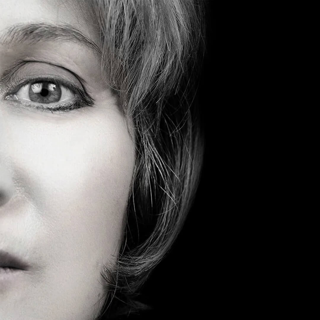 Imagem artística em fundo preto mostrando metade do rosto de uma pessoa em close-up.