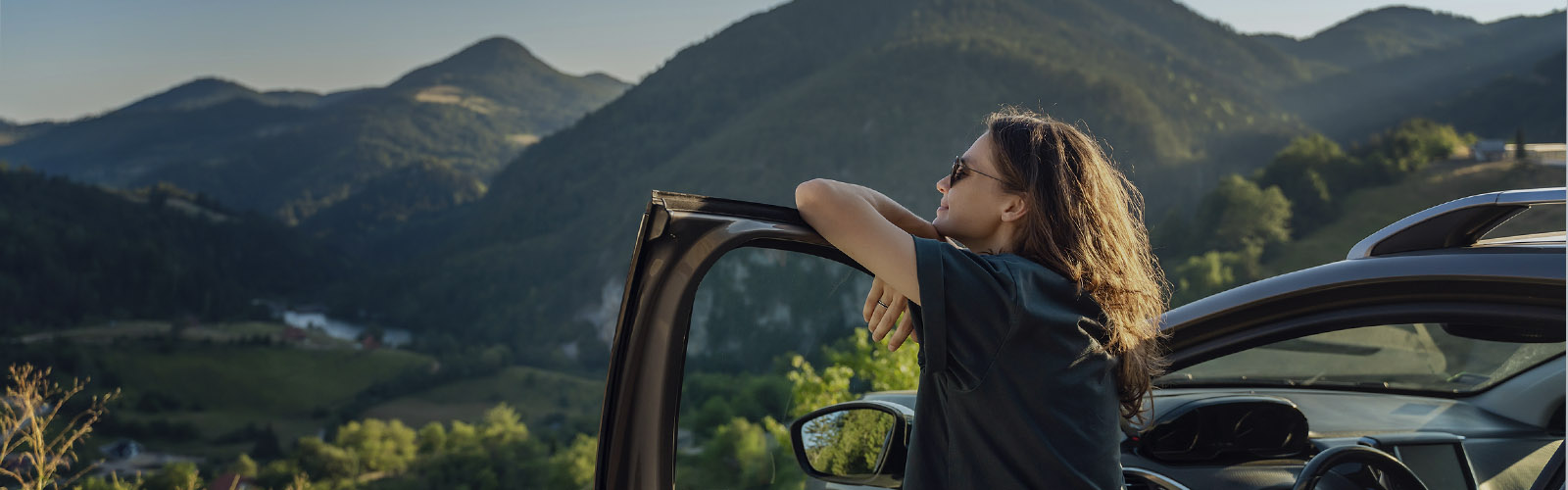 Ambiente de tranquilidade e segurana com mulher a observar paisagem  encostada à porta do carro
