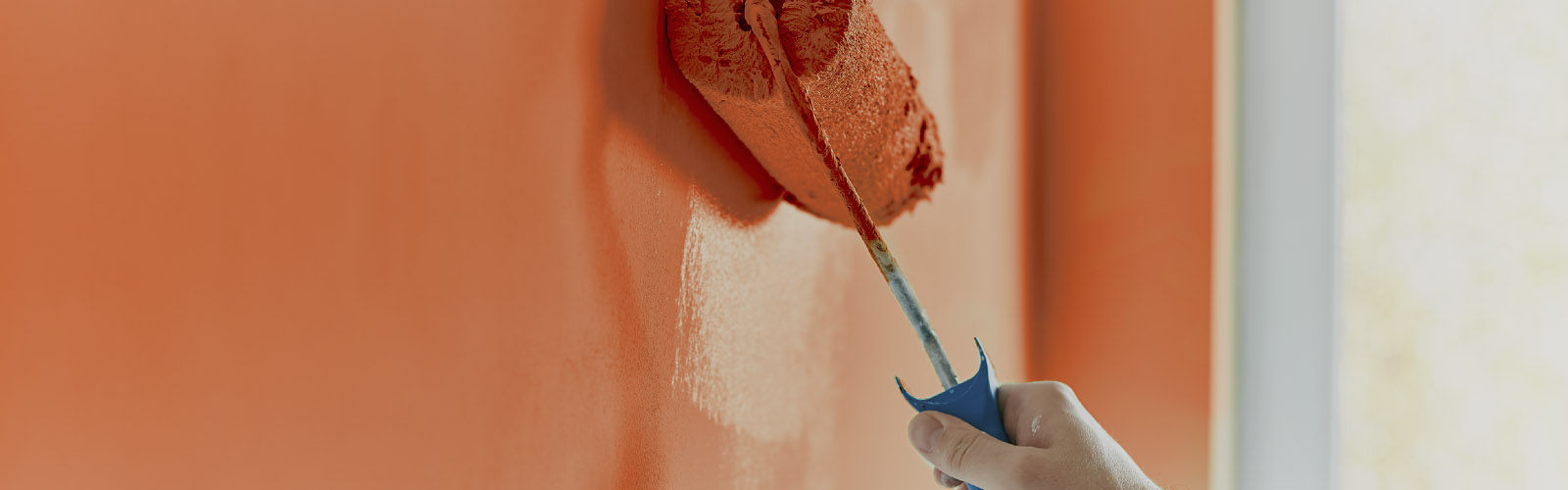 Trincha de tinta encarnada é usada numa parede em obras