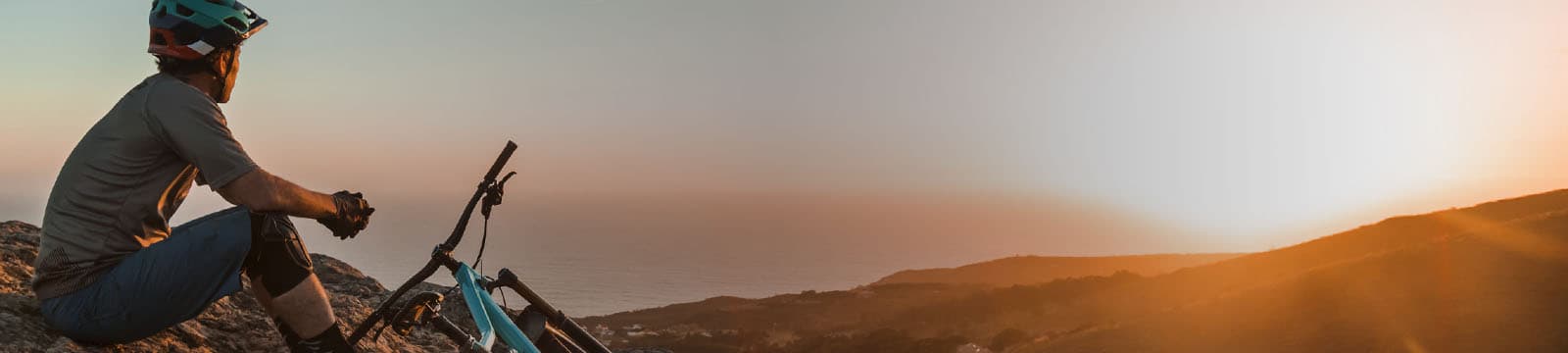 Homem observa o horizonte com montanhas da sua bicicleta