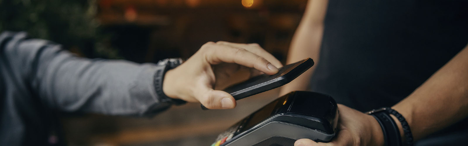 smartphone aproxima-se de dispositivo de pagamento, POS, para fazer um pagamento MB Way em loja