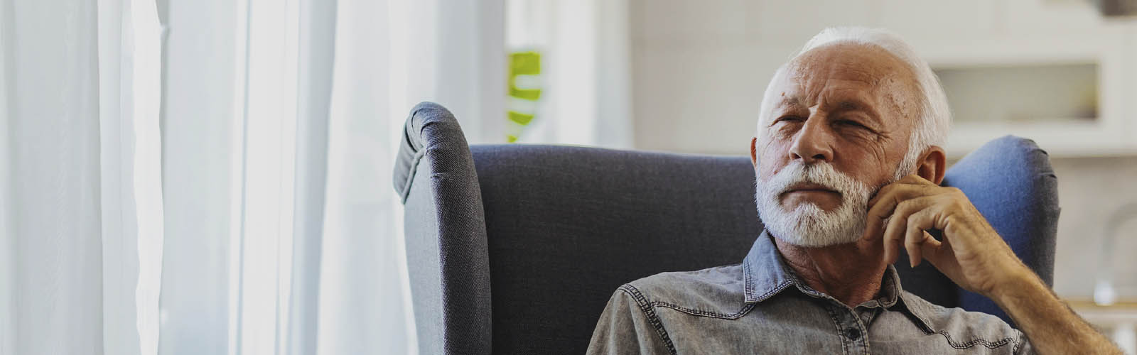 homem idoso com barbas sentado confortável e a gozar a sua reforma